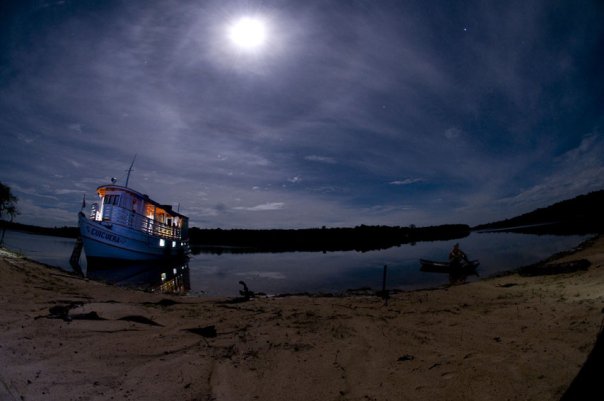 Embarcações na margem de um rio sob o céu noturno